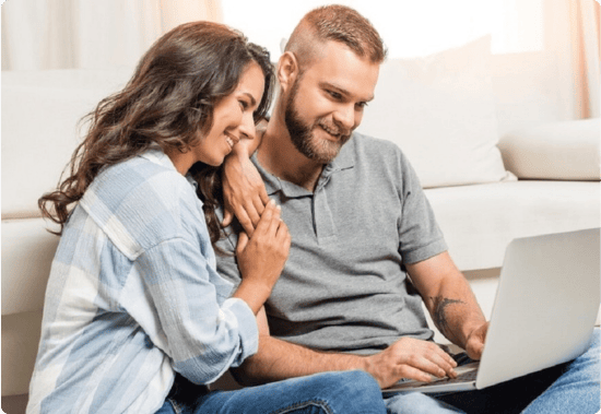 Man en vrouw zittend op de grond met een laptop, lachend naar het scherm, symbool voor de toegankelijkheid en betrokkenheid bij beleggen in aandelen.