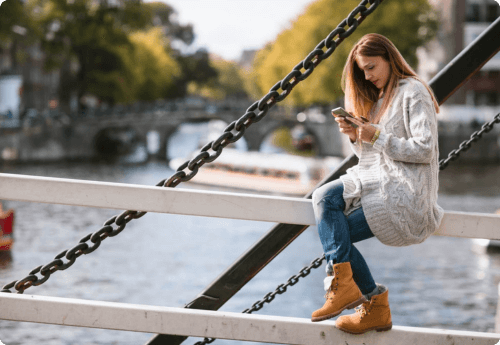 Vrouw met telefoon zittend op een brug