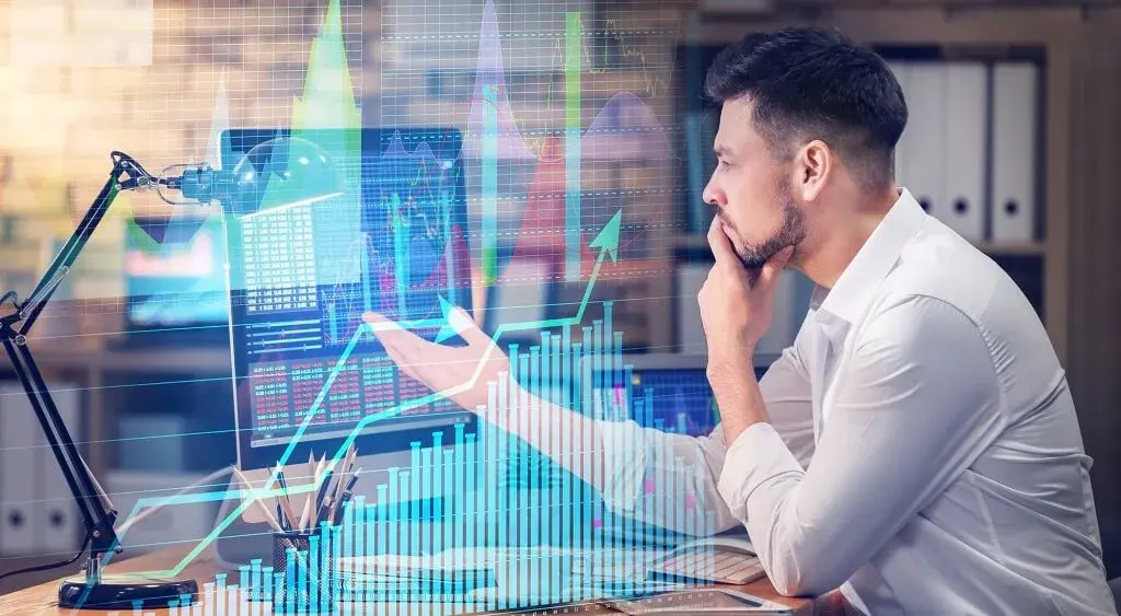 Man achter bureau met een waas van stocks over hem heen bezig met aandelen kopen