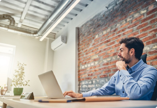 Man op kantoor kijkend naar de 25 AEX-bedrijven op zijn laptop