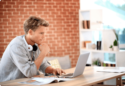 Man met koptelefoon kijkend naar laptop