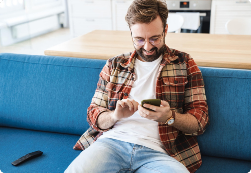 Man zittend in bank kijkend naar telefoon