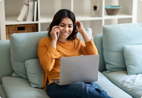 Vrouw zittend in de bank bellend met een laptop op haar schoot