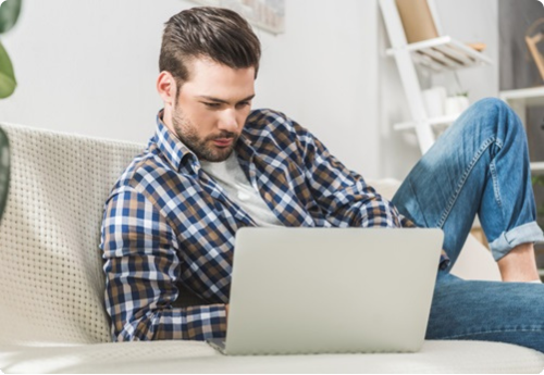 man liggend in de bank met een laptop