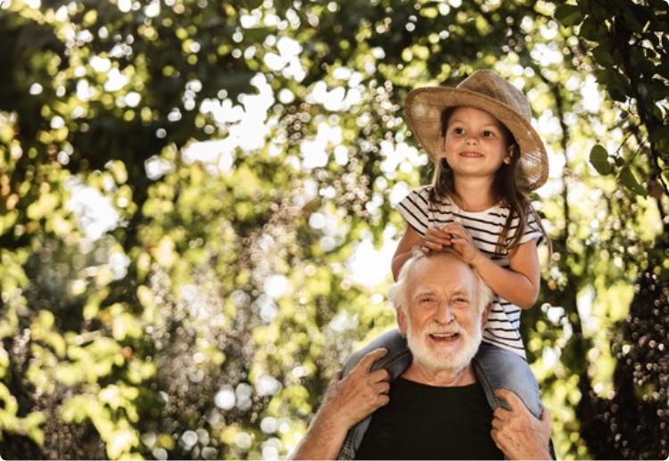 Meisje bij haar opa op haar schouders met een rieten hoed op