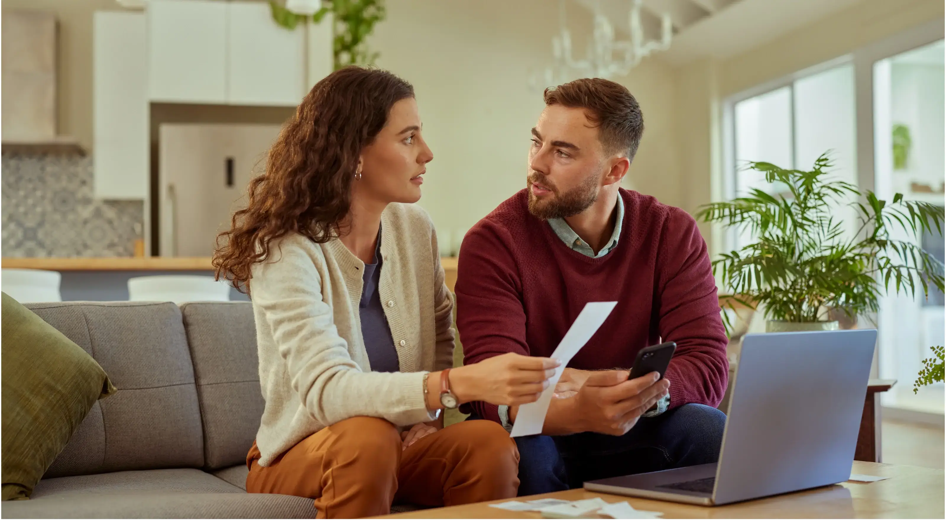 Koppel bekijkt samen hun financiële situatie en gezamenlijke beleggingen via laptop aan de keukentafel.